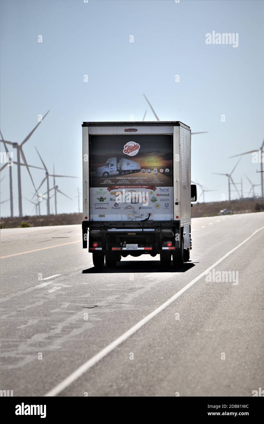 LKW fährt auf der Autobahn vorbei Windmühle Stromgeneratoren in Die hohe Wüste von Kalifornien USA Stockfoto