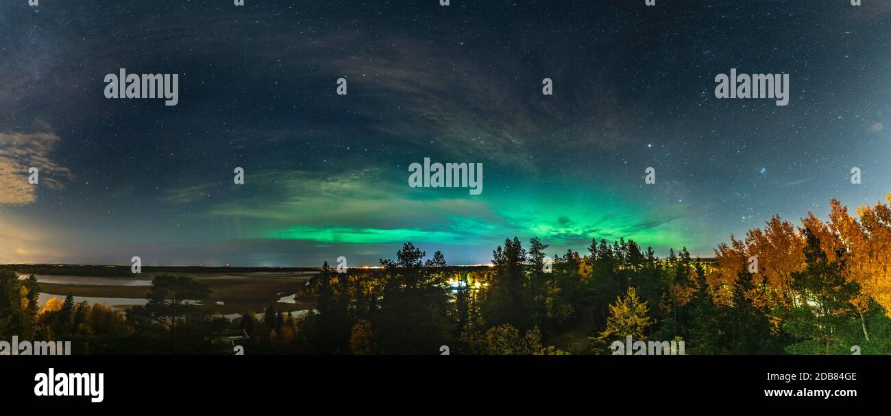 Landschaftlich schöne Aurora Borealis Panoramafoto über den ganzen Horizont, über Herbstbirke und Kiefernwald, Stadtlichter in schwedischer Landschaft in der Nähe von U Stockfoto