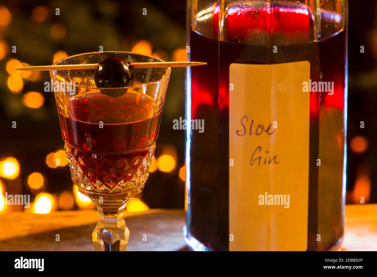 Flasche und Glas selbstgemachten Schlehen Gin. Mit einer Schlehbeere auf dem Glas. Stockfoto