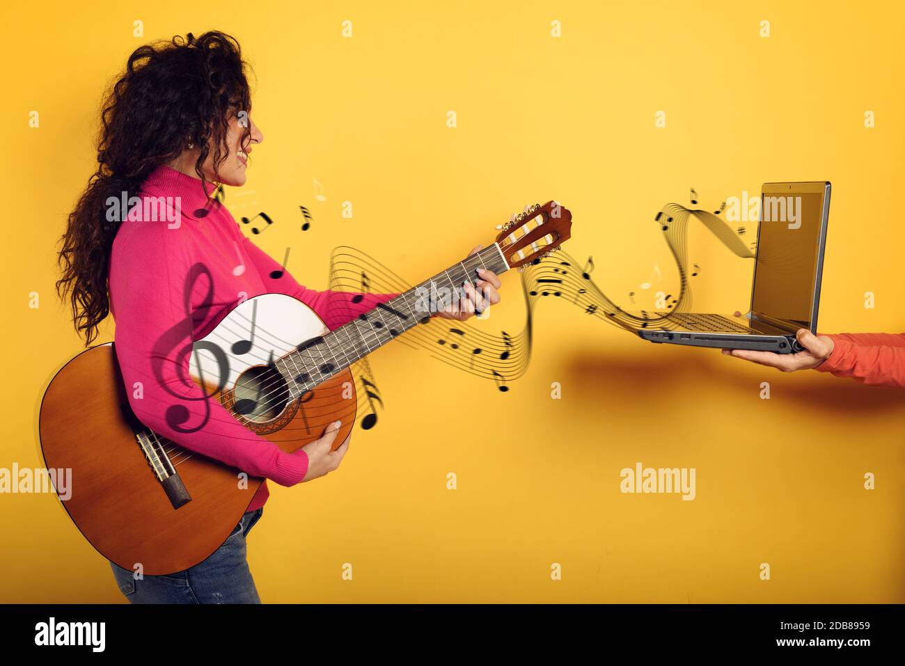 Happy Woman folgt einem Gitarrenunterricht online. Gelber Hintergrund Stockfoto