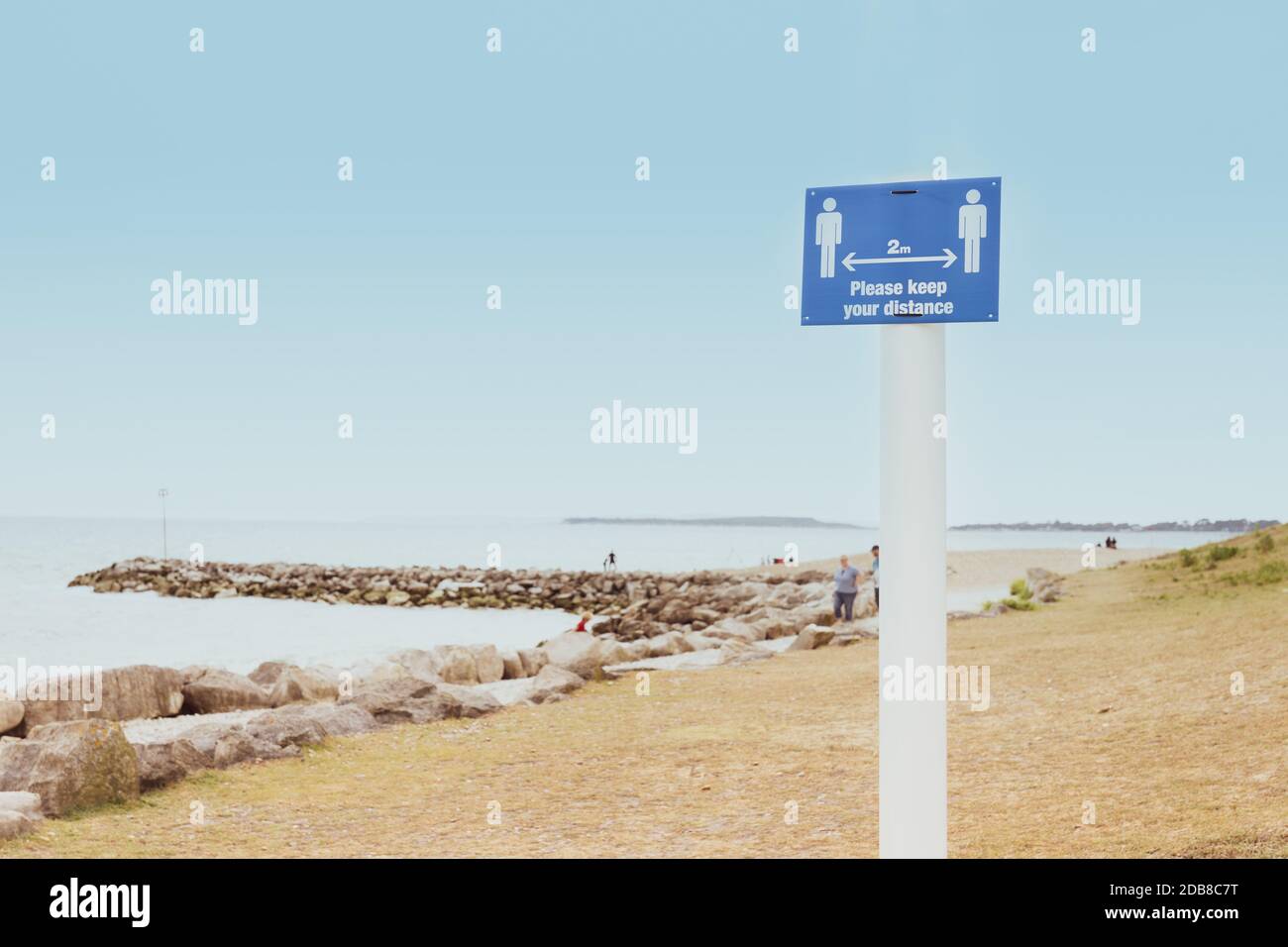 Nachricht mit Bitte halten Sie Ihren Abstand auf dem Schild stehen am Strand. Neue normale soziale Distanzierungsmaßnahmen an öffentlichen Orten während eines Covid-19 Stockfoto