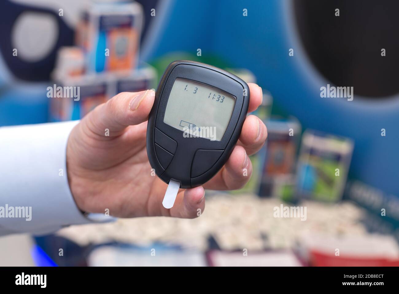 Die Hand hält ein Blutzuckermessgerät mit einem Teststreifen auf einem unfokussierten Hintergrund. Das Konzept der Diabetes-Prävention. Stockfoto