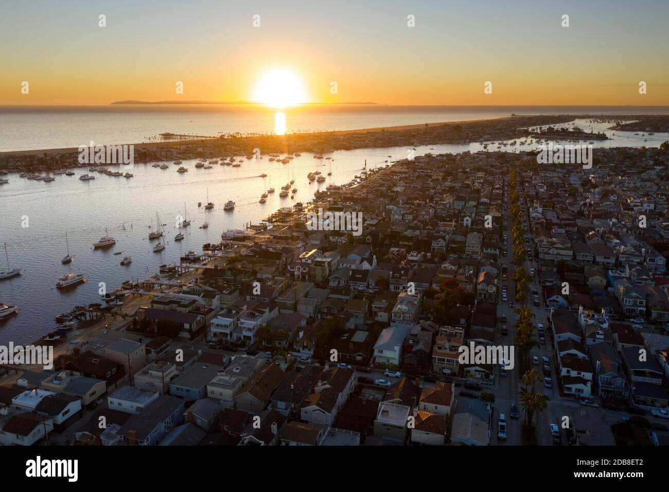Leuchtender Sonnenuntergang über Balboa Island und Newport Beach Hafen Aus der Luft Stockfoto