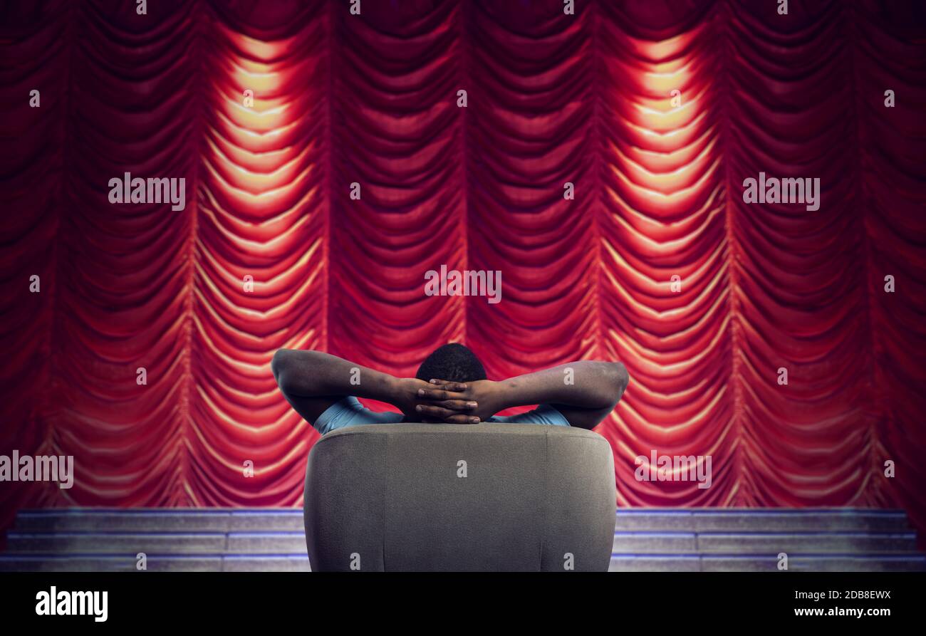 Mann, der sich auf einem Sessel entspannt und eine Show sieht Ein Theater Stockfoto