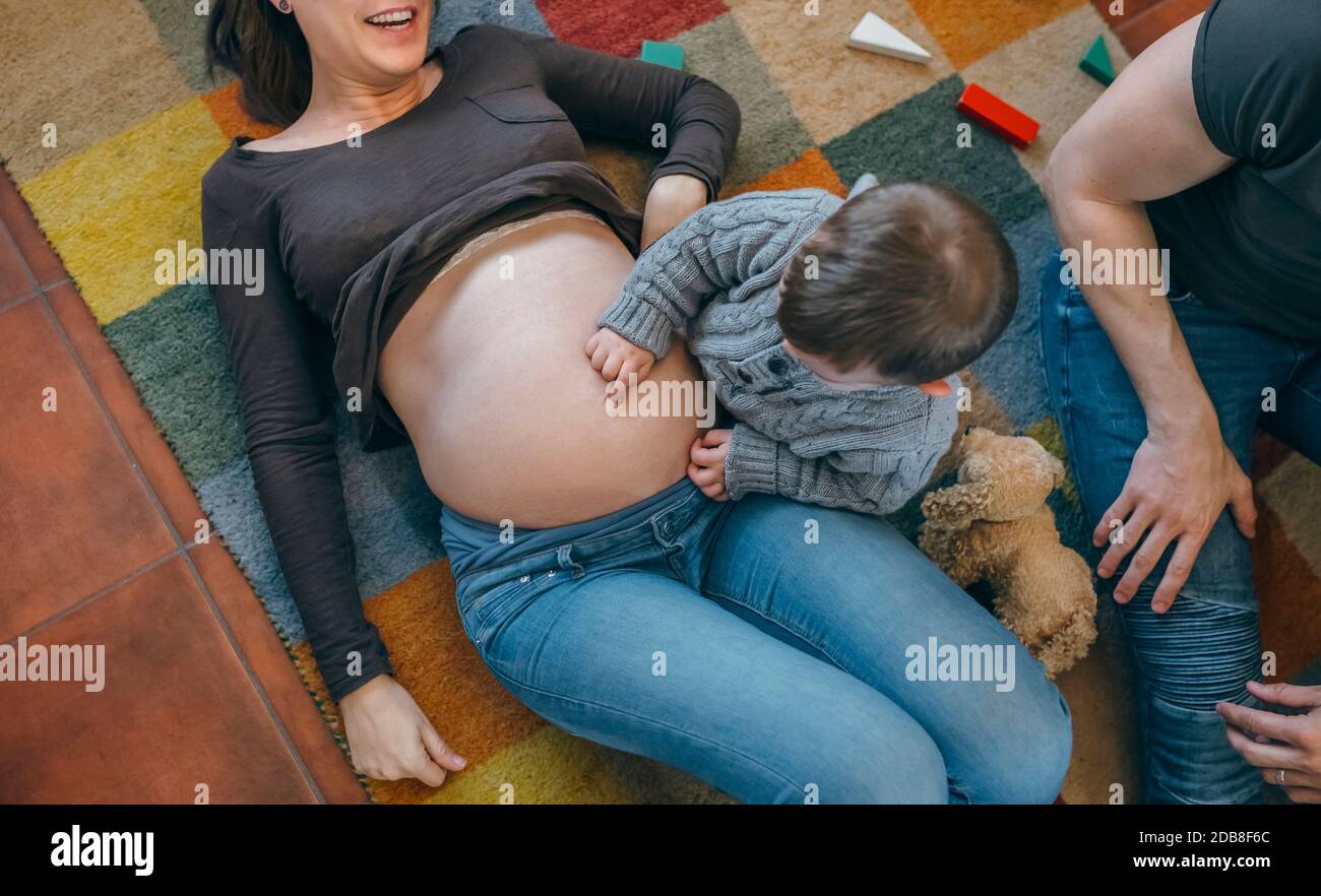 Kleinkind kitzelt den Bauch seiner schwangeren Mutter Stockfoto