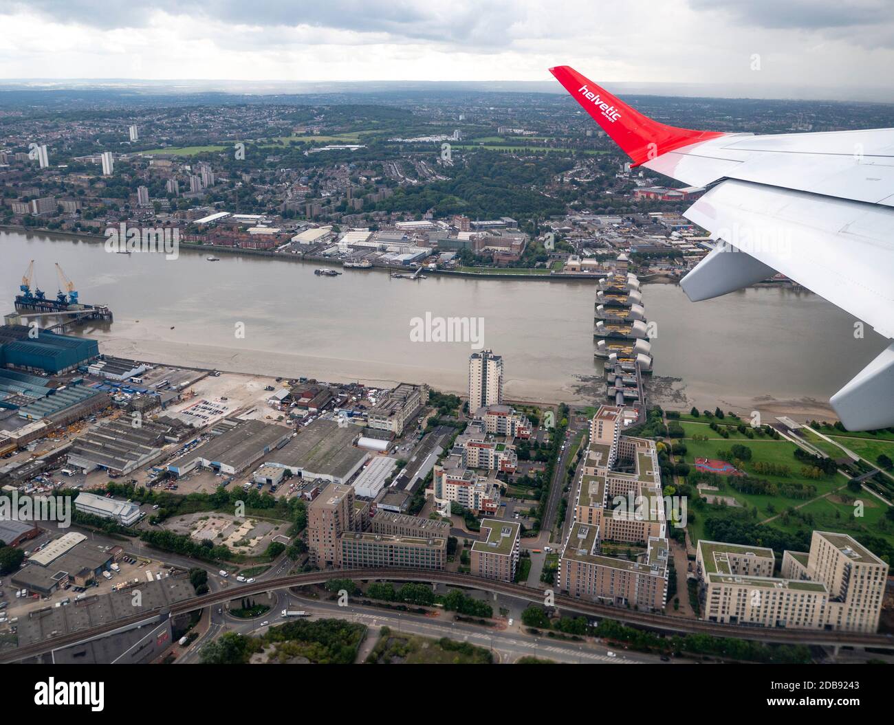 Ein Schweizer Flugzeug der Helvetic Airline hebt von London ab Stadtflughafen in Richtung Zürich mit dem Flugzeug über die Thames Barrier Stockfoto