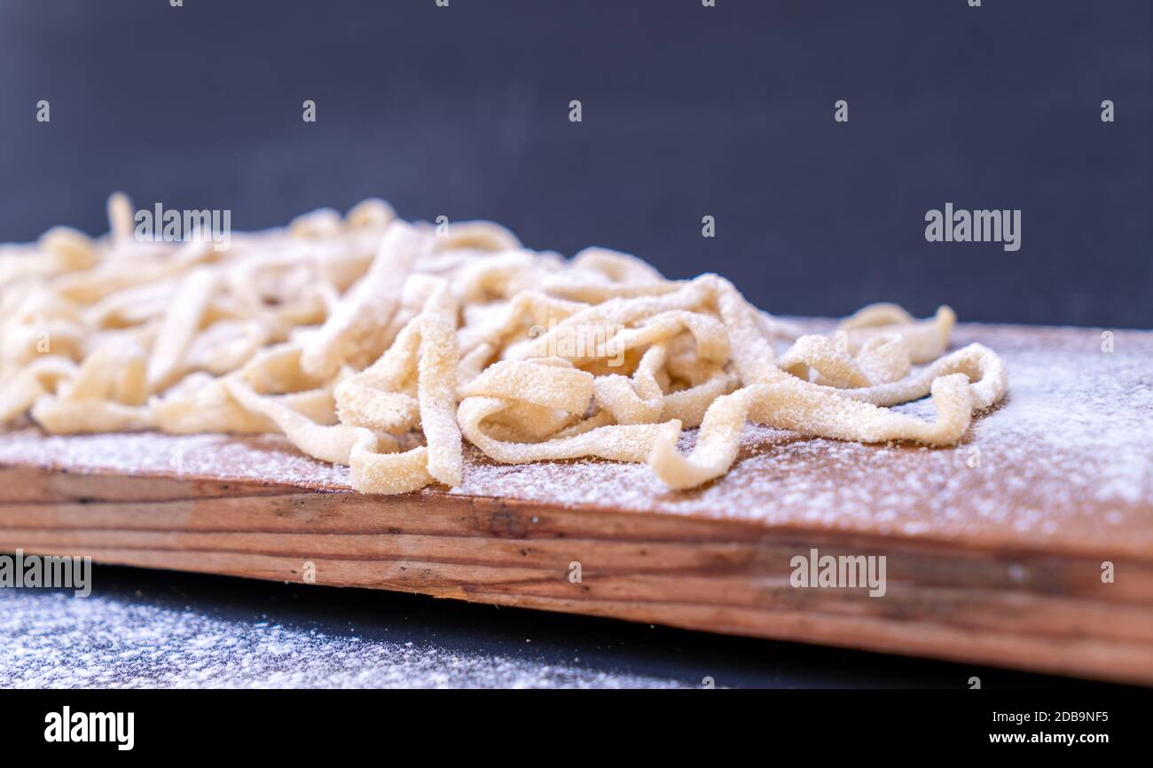 Rohe Pasta auf Holztisch mit Nudelholz und Radschneider Stockfoto