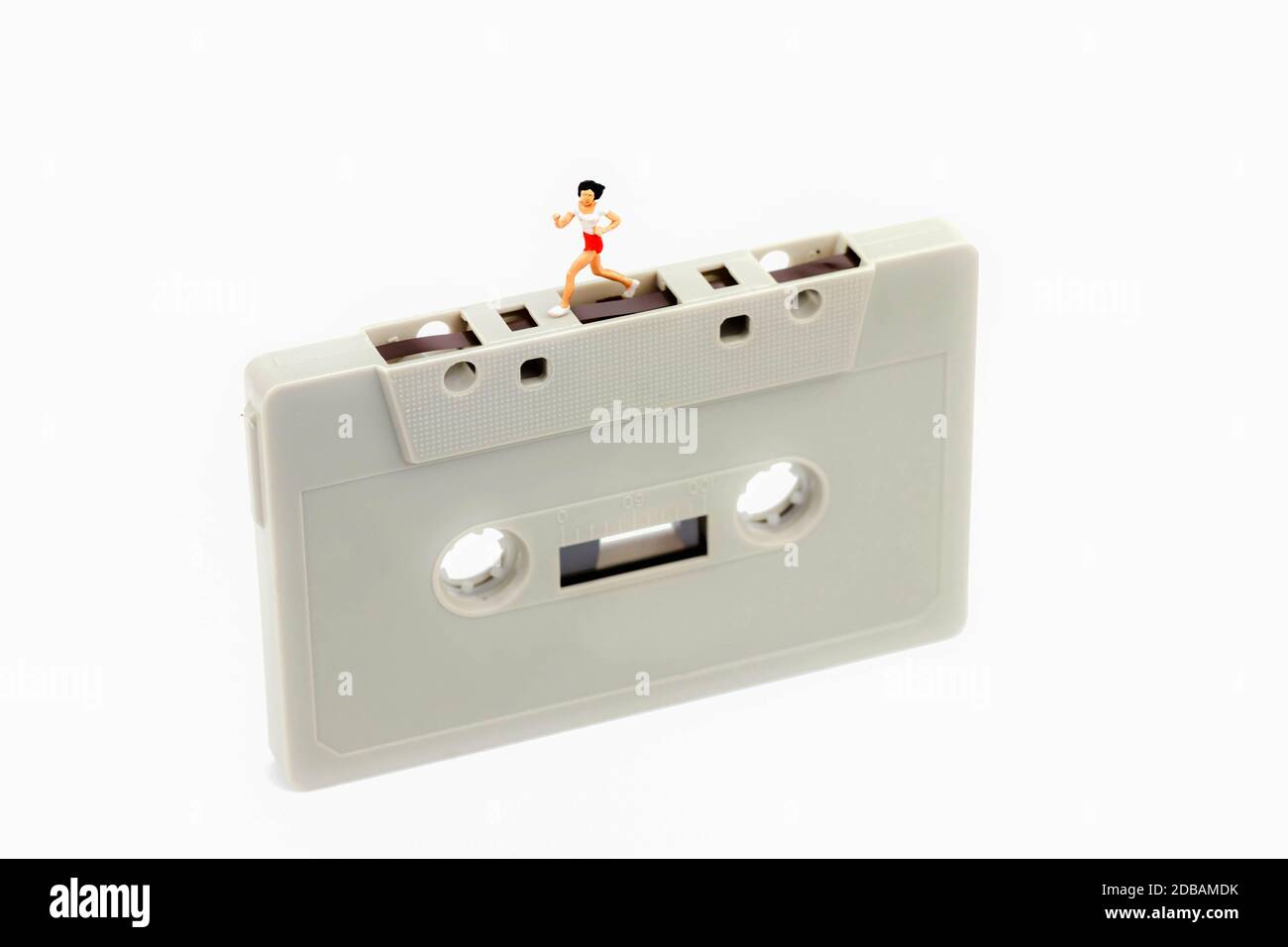 Miniatur Frau läuft auf einer Musikkassette Stockfoto