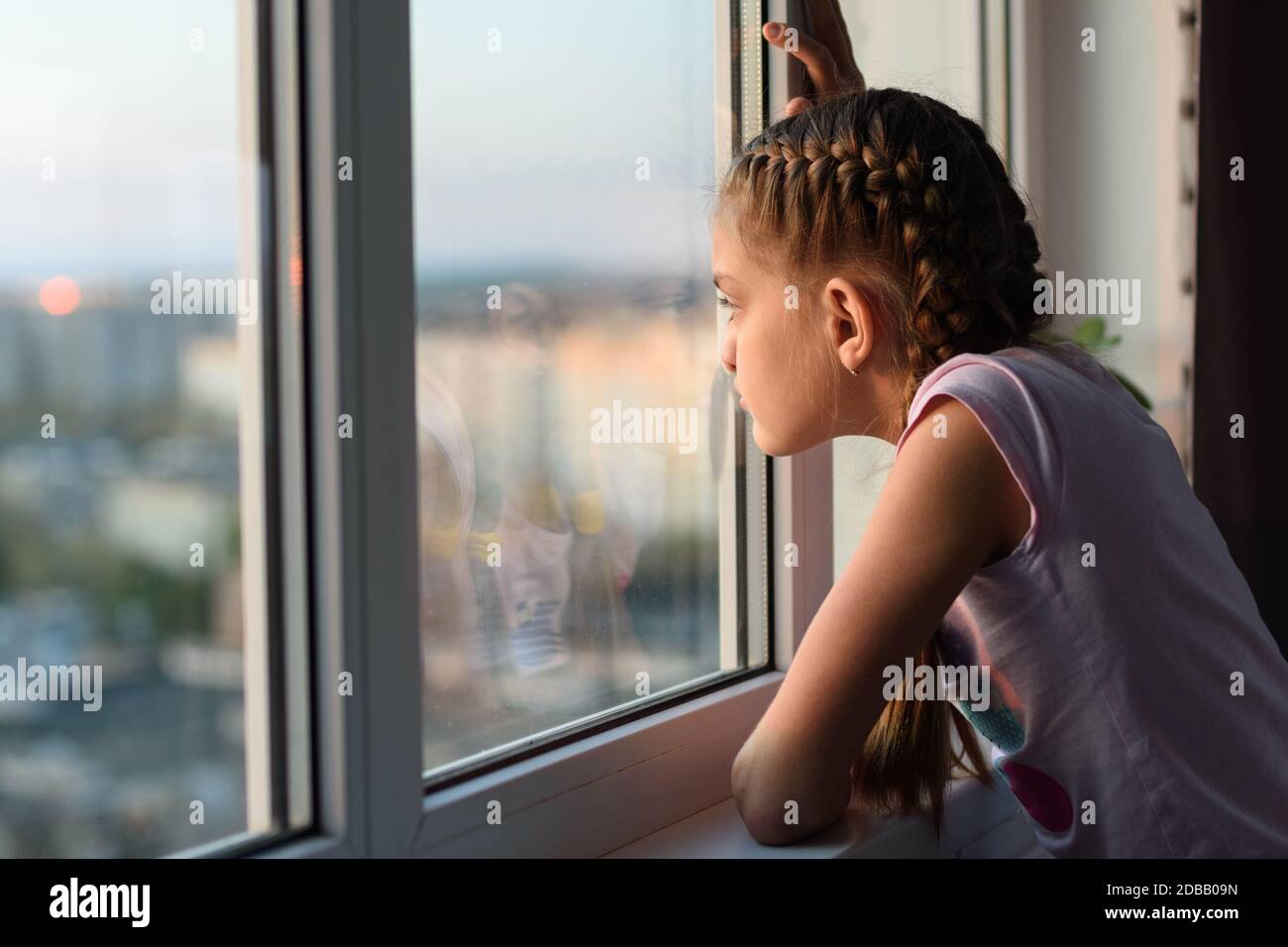 Mädchen gelangweilt zu Hause in Quarantäne schaut aus dem Fenster Stockfoto