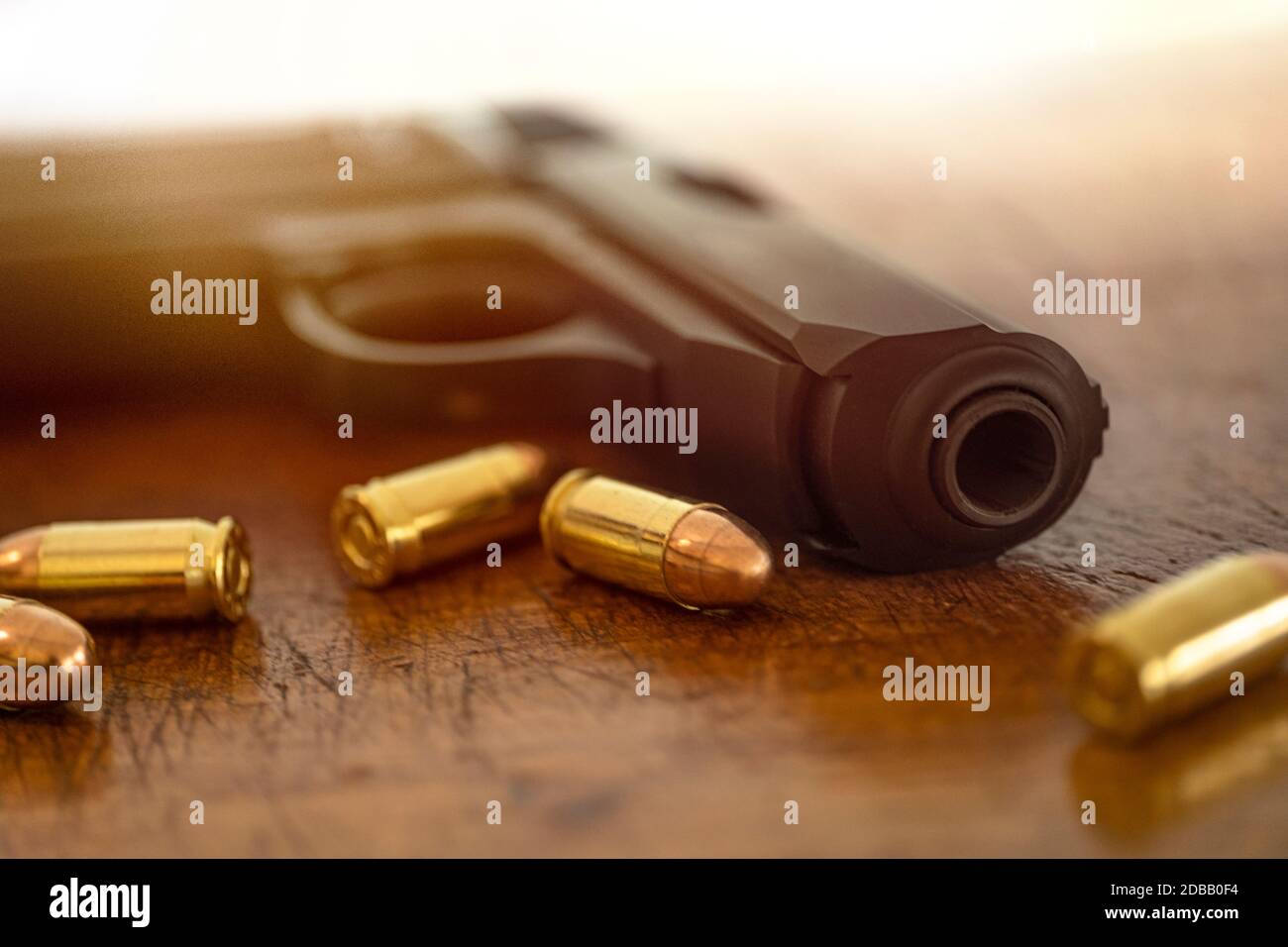 Goldkugeln und Pistole auf Holzoberfläche Stockfoto