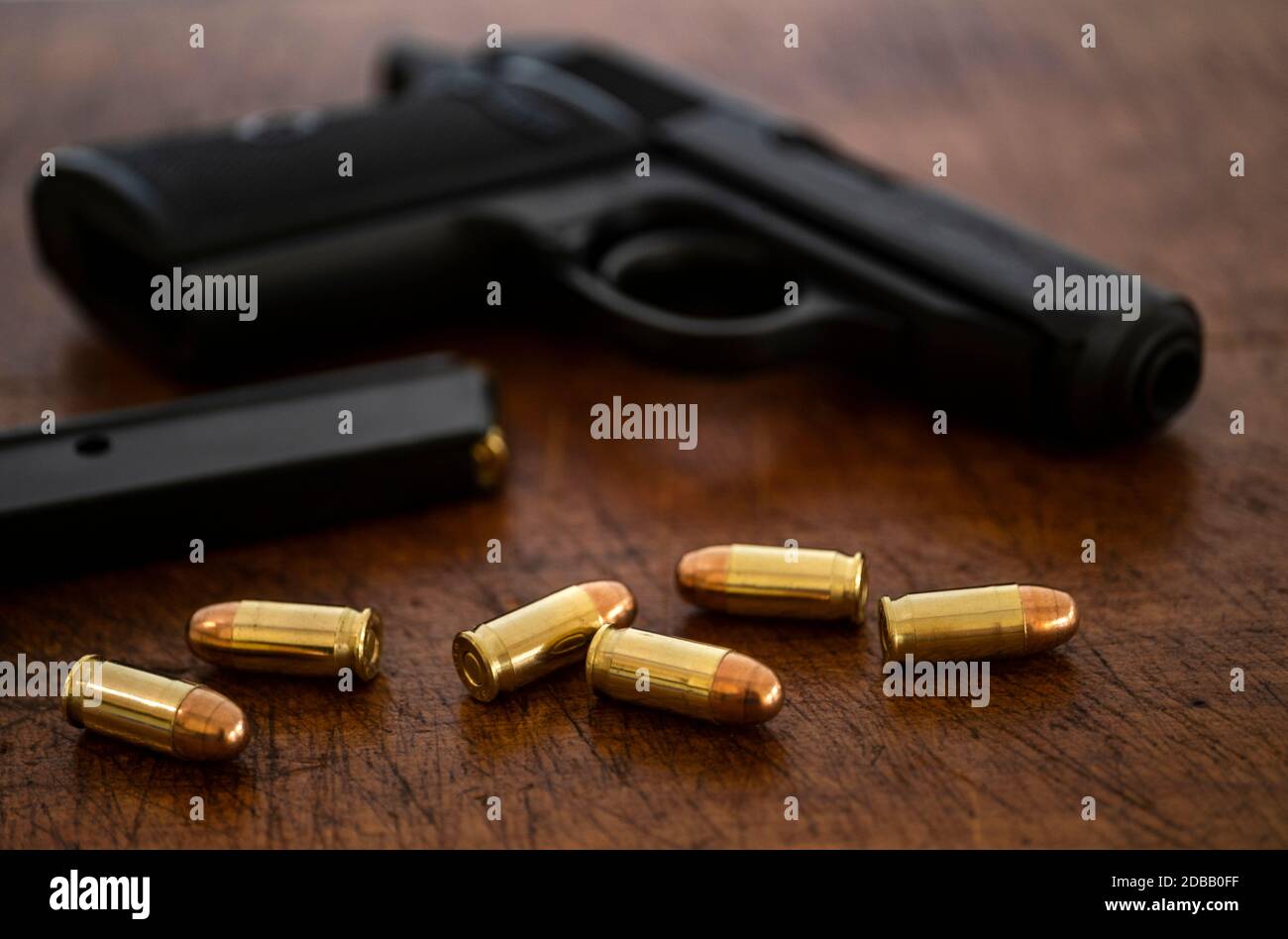 Goldkugeln und Pistole auf Holzoberfläche Stockfoto
