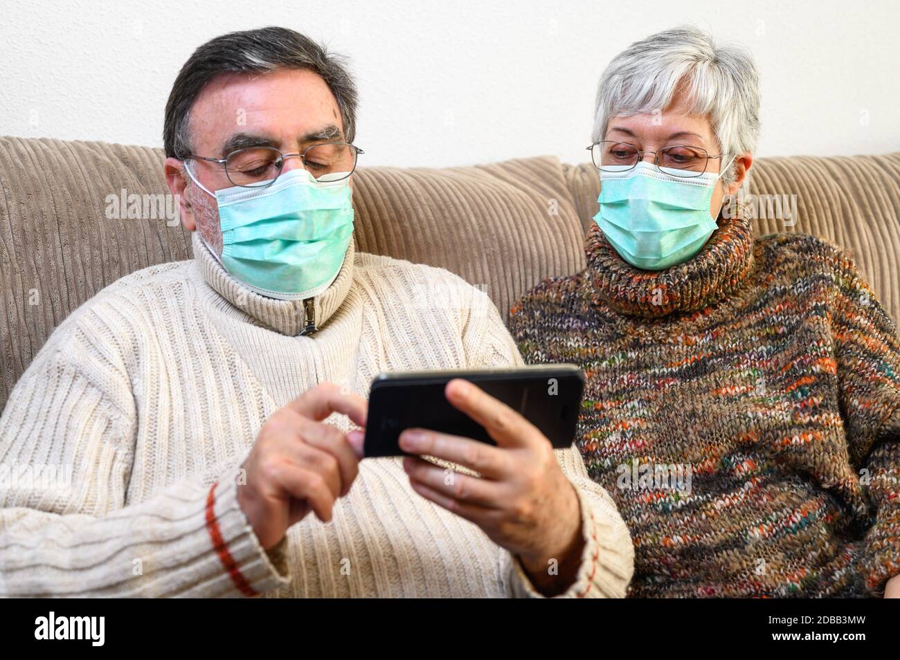 Coronavirus. Bleiben Sie zu Hause, Lifestyle.Fröhliche ältere Paar auf einem Sofa auf einer Quarantäne zu Hause sitzen, einen Videoanruf mit dem Smartphone. Senio Stockfoto