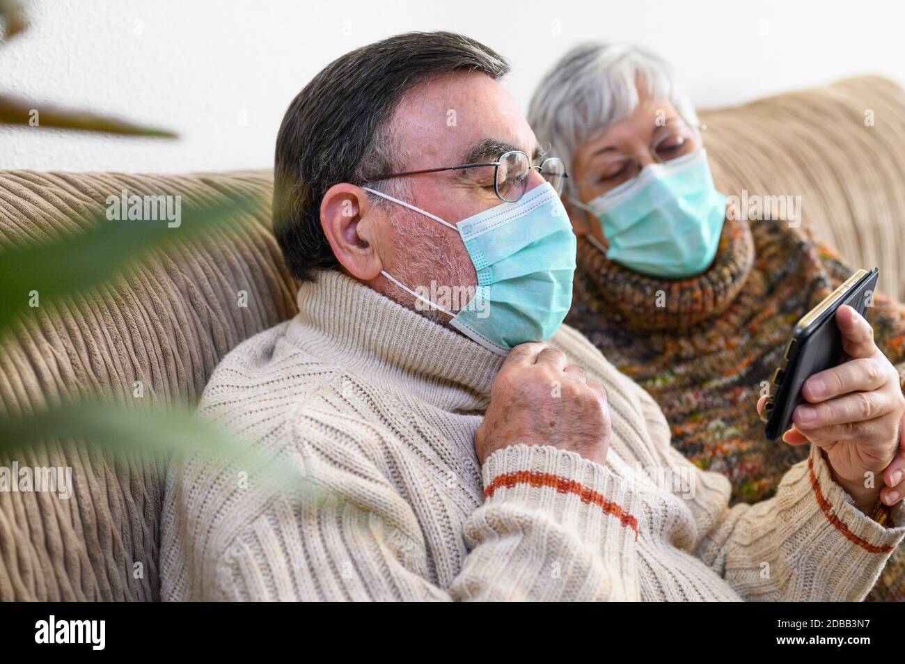 Coronavirus. Bleiben Sie zu Hause, Lifestyle.Fröhliche ältere Paar auf einem Sofa auf einer Quarantäne zu Hause sitzen, einen Videoanruf mit dem Smartphone. Senio Stockfoto