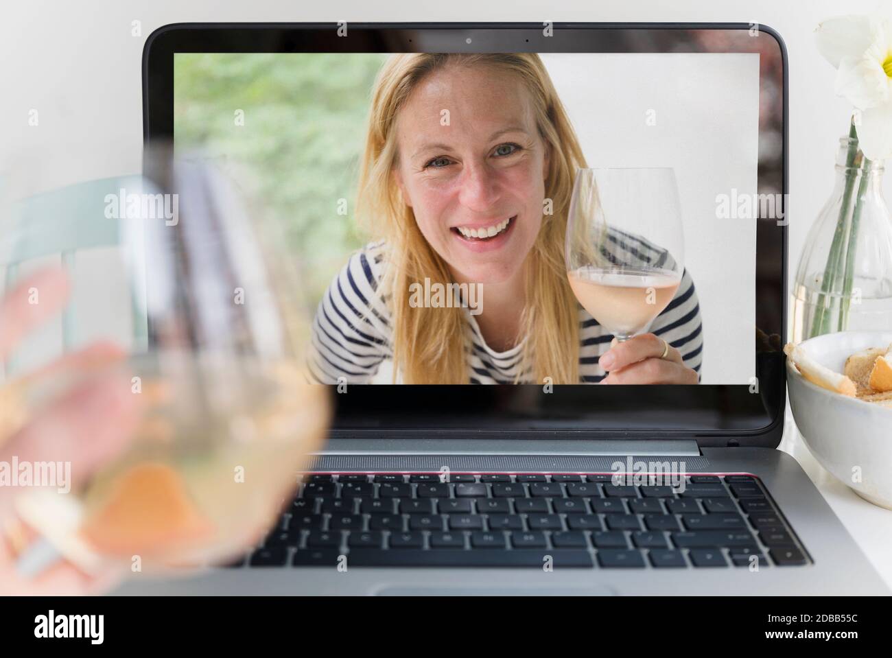 Frau trinkt Wein mit Freund online Stockfoto