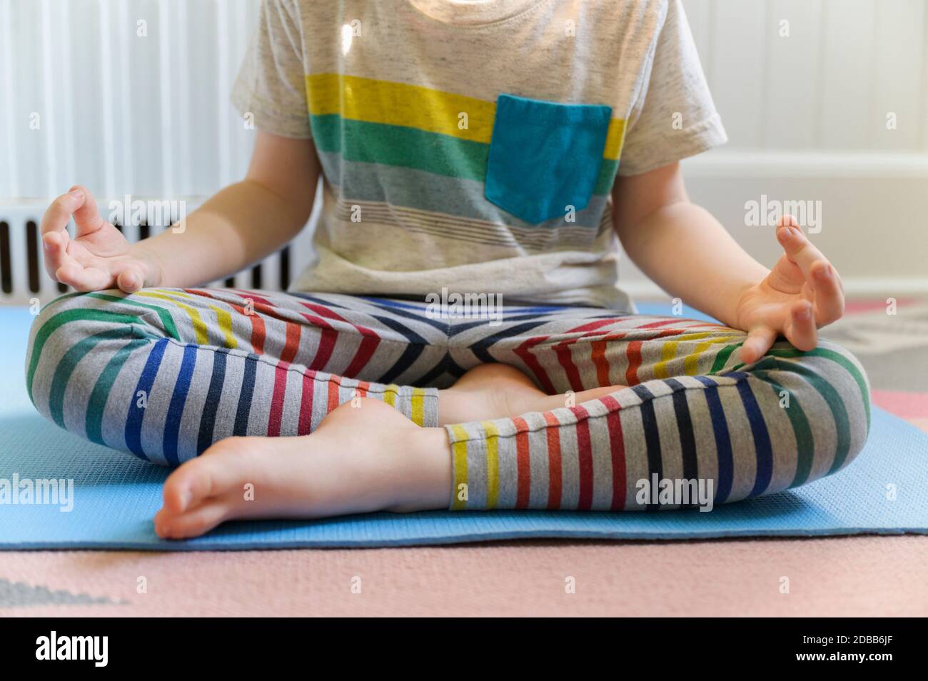 Junge (4-5) übt Yoga auf Matte Stockfoto