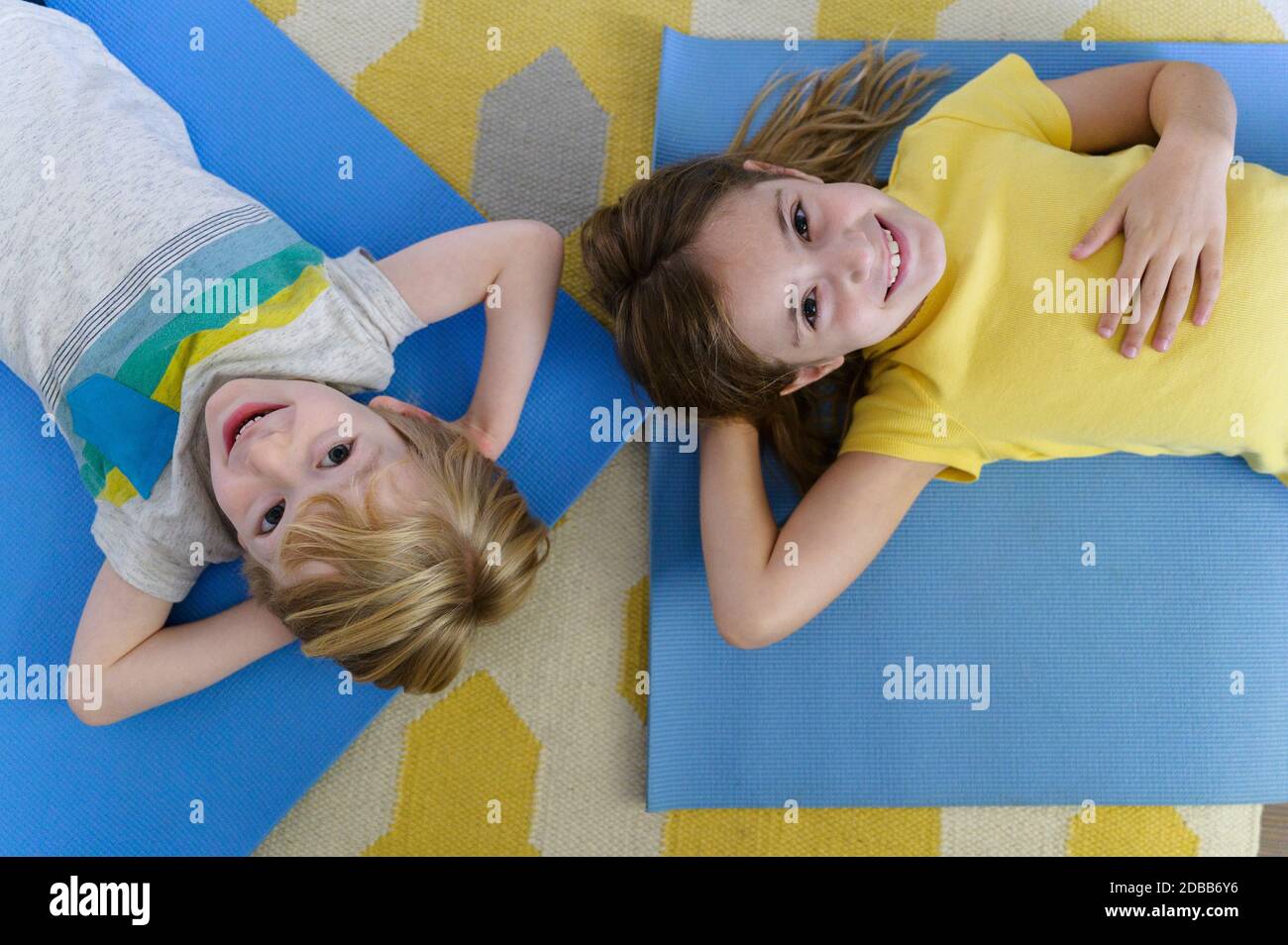 Oben Porträt des Jungen (4-5) und Mädchen (6-7) liegend auf Yogamatten Stockfoto