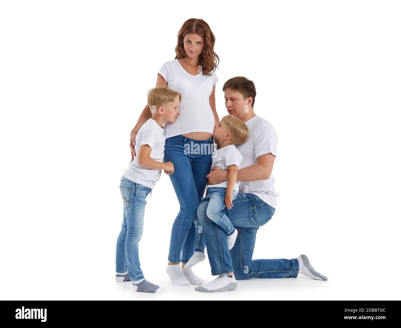 Freundliche Familie. Ehemann mit zwei Söhnen lächeln und umarmen schwangere Frau, isoliert auf einem weißen Hintergrund. Glückliche Eltern. Schwangere Mutter und f Stockfoto
