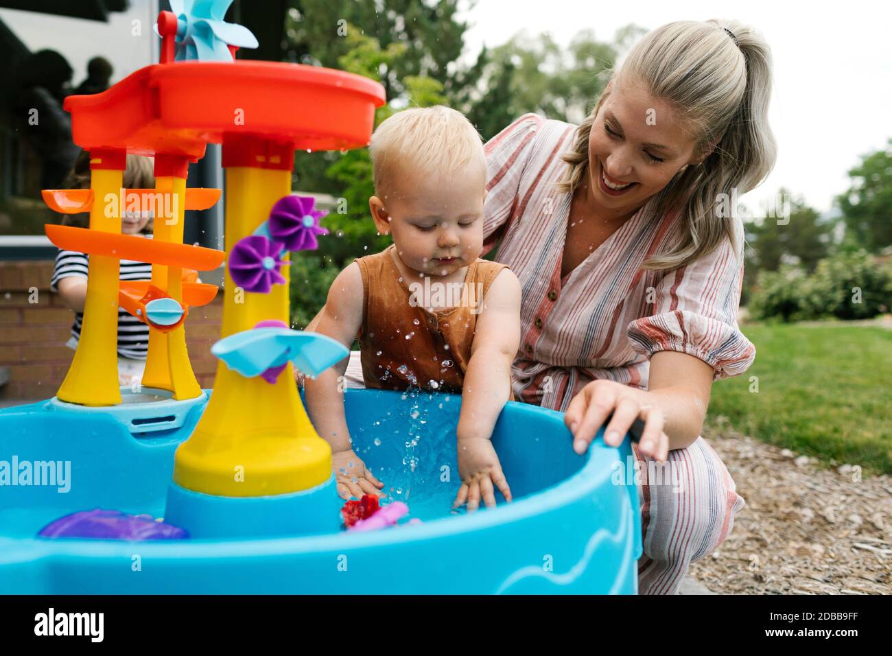 Mutter mit Kleinkind (18-23 Monate) Spielen mit Wasser im Garten Stockfoto