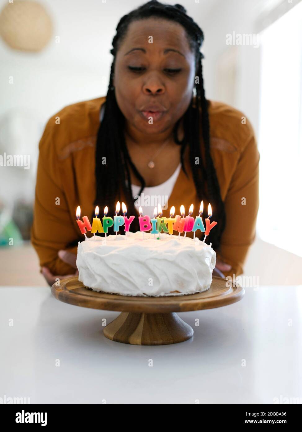 Frau bläst Kerzen auf Geburtstagstorte Stockfoto