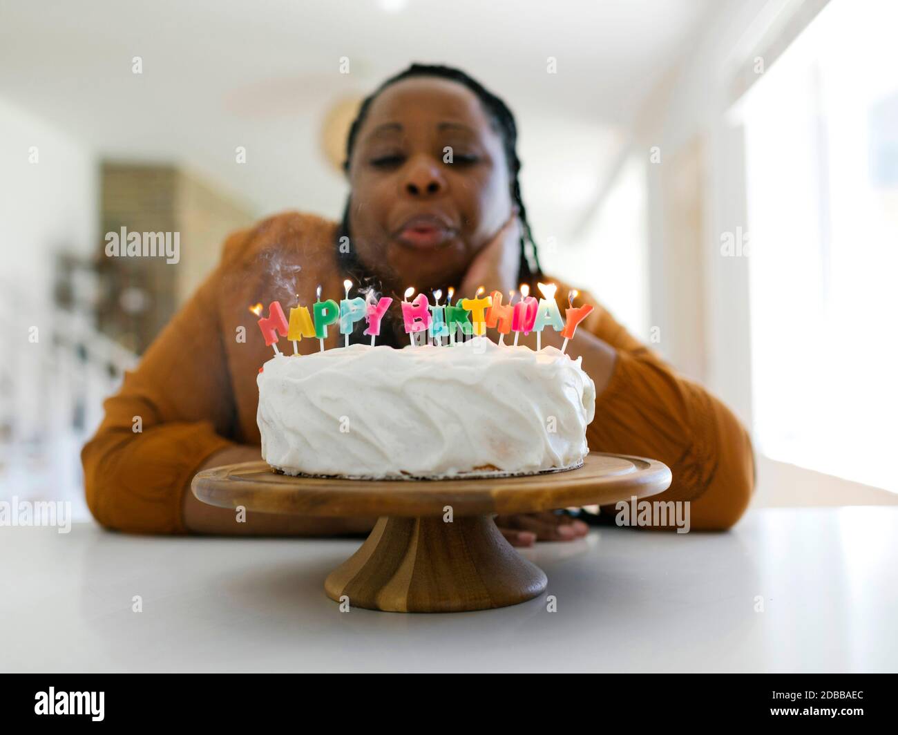 Frau bläst Kerzen auf Geburtstagstorte Stockfoto