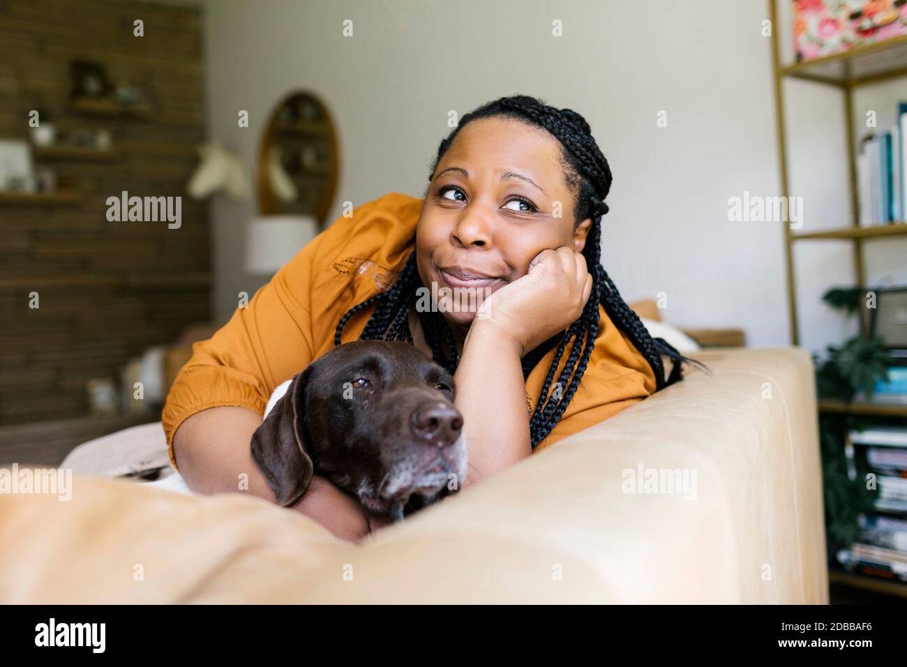 Frau liegt auf dem Sofa mit ihrem Hund Stockfoto