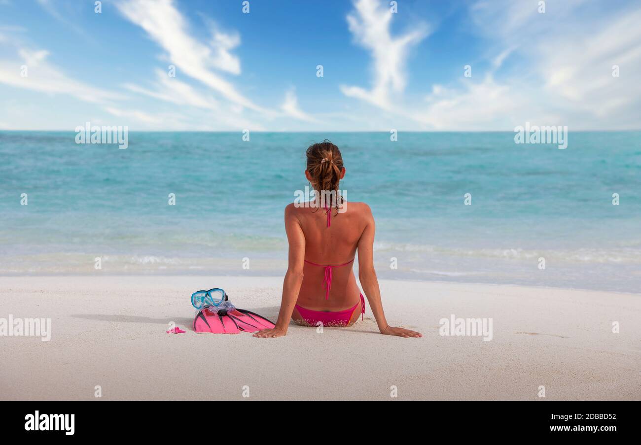 Malediven, Rückansicht einer Frau im Bikini am Strand sitzend Stockfoto