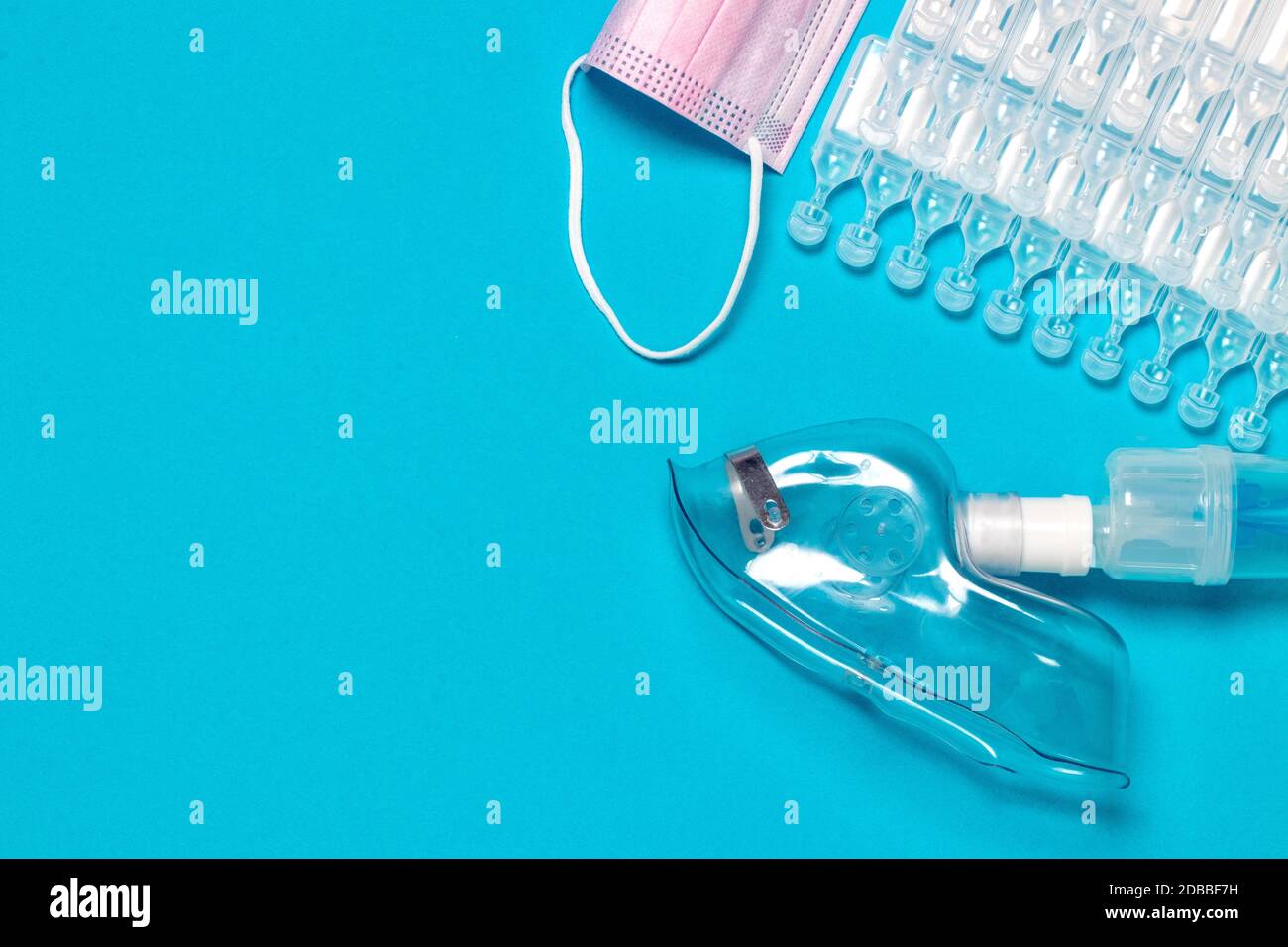 Behandlungskonzept für Coronavirus. Eine medizinische Gesichtsmaske oder Vernebler zur Behandlung der Atemwege weitere Ampullen und eine chirurgische Maske flach gelegt Stockfoto