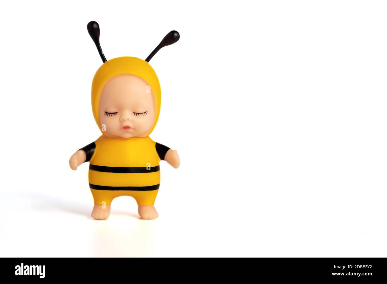 Niedliche kleine Puppe in einem Bienenkostüm mit geschlossenen Augen. Steht auf einem weißen isolierten Hintergrund. Ein entzückendes Spielzeug für ein Geschenk oder ein Kinderspiel. Weichfokus. Stockfoto