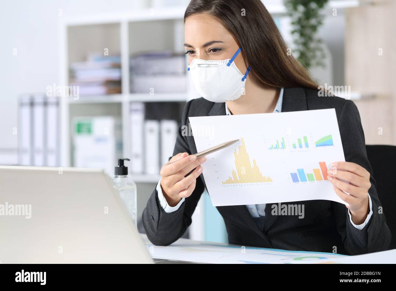 Glückliche Exekutive Frau mit Schutzmaske zeigt Wachstum Graph Bericht auf Videocall auf Laptop im Büro Stockfoto