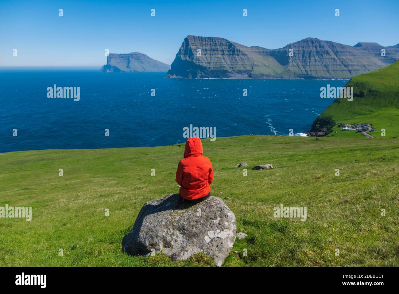 Dänemark, Färöer, Klaksvik, Trolleas, Frau, die auf Felsen sitzt und auf den Ozean schaut Stockfoto