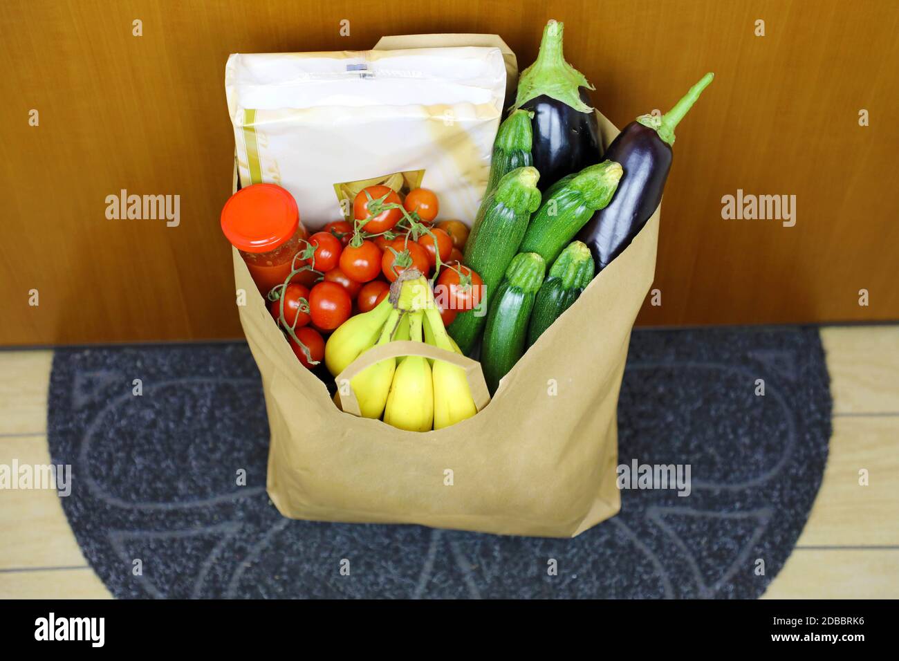 COVID-19 Pandemic Coronavirus HauslieferungLebensmittel Lebensmitteltasche hinter der Tür auf Matte für Coronavirus Krankheit Verbreitung Sicherheit gelassen. Vorsichtsmaßnahme aga Stockfoto