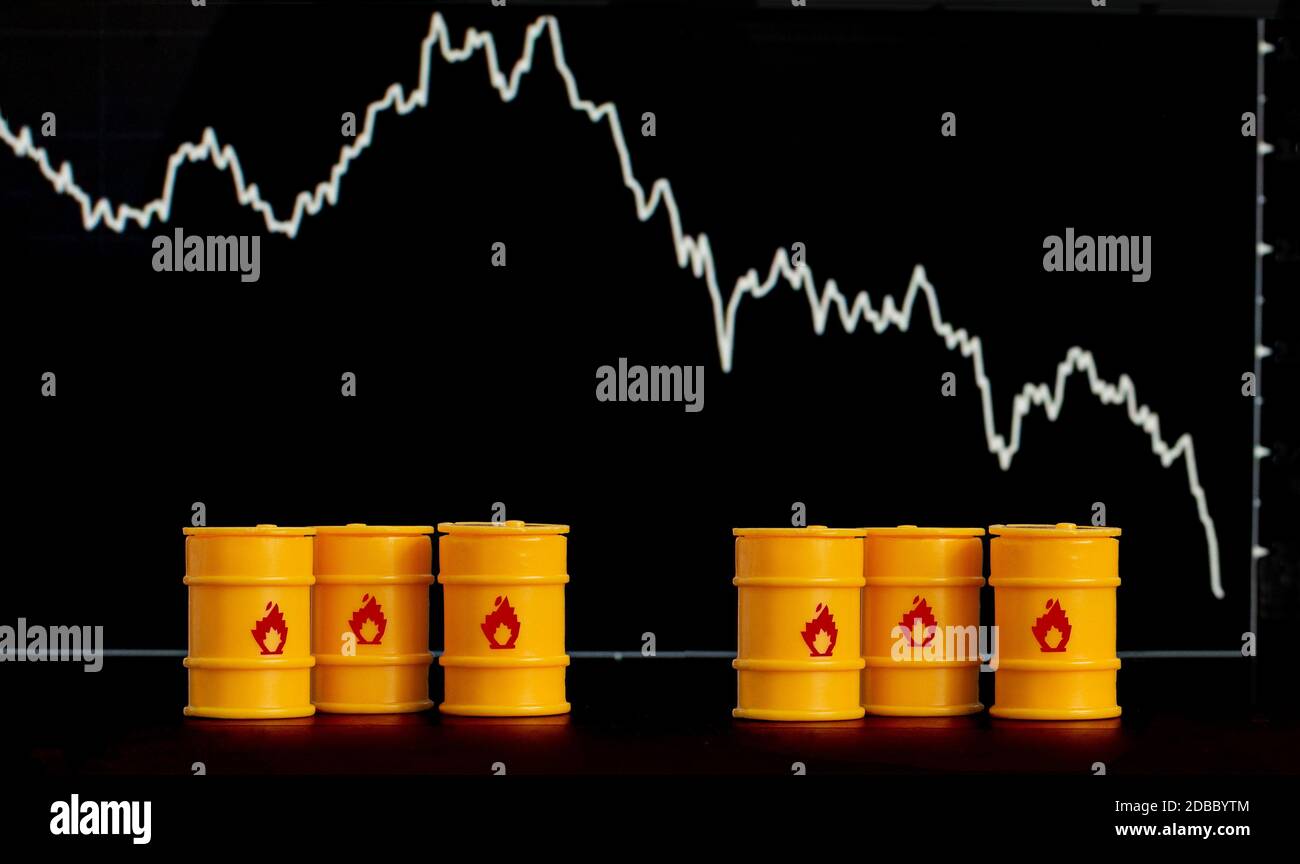 Barrel Öl und Benzin auf dem Hintergrund eines Bildschirms mit einem fallenden Diagramm. Stockfoto