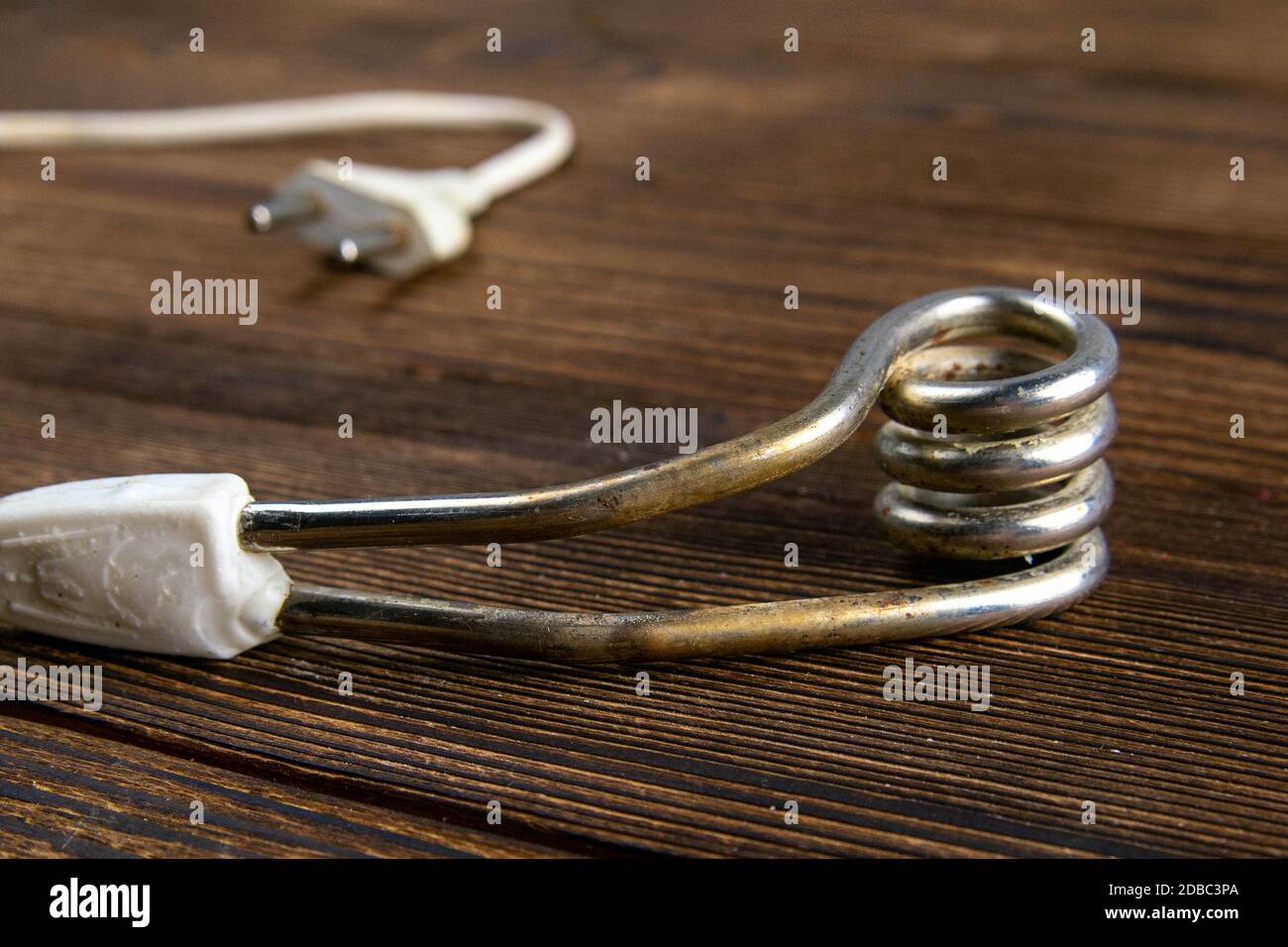 Alte Tauchwasserheizung auf dunklem Holzhintergrund. Nahaufnahme. Stockfoto