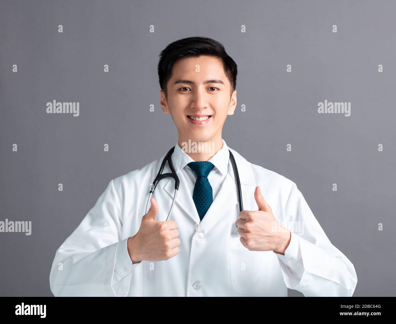 Portrait des männlichen asiatischen jungen Arztes mit Daumen nach oben Stockfoto