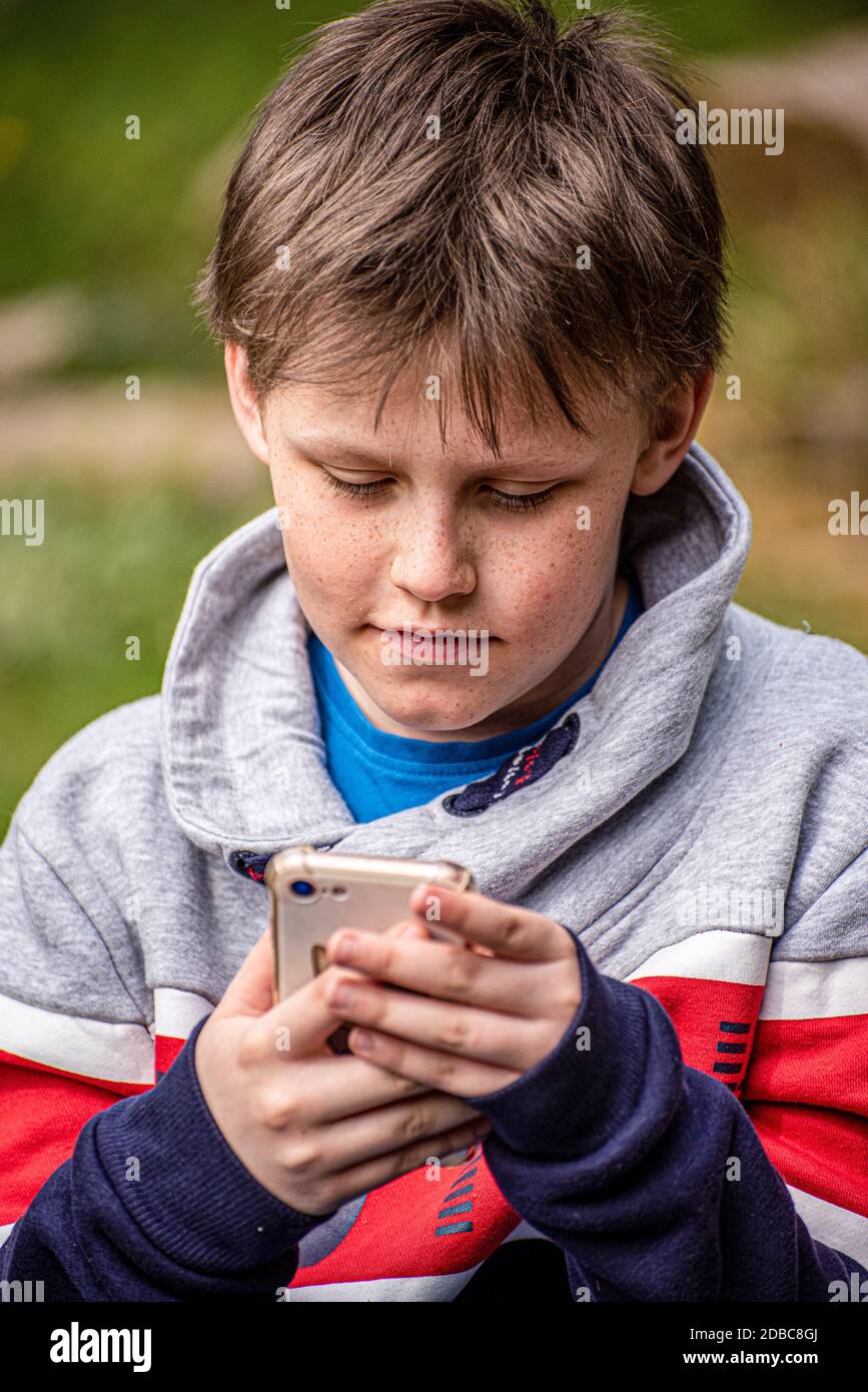 Junge, der sein Mobiltelefon im Freien ansieht Stockfoto