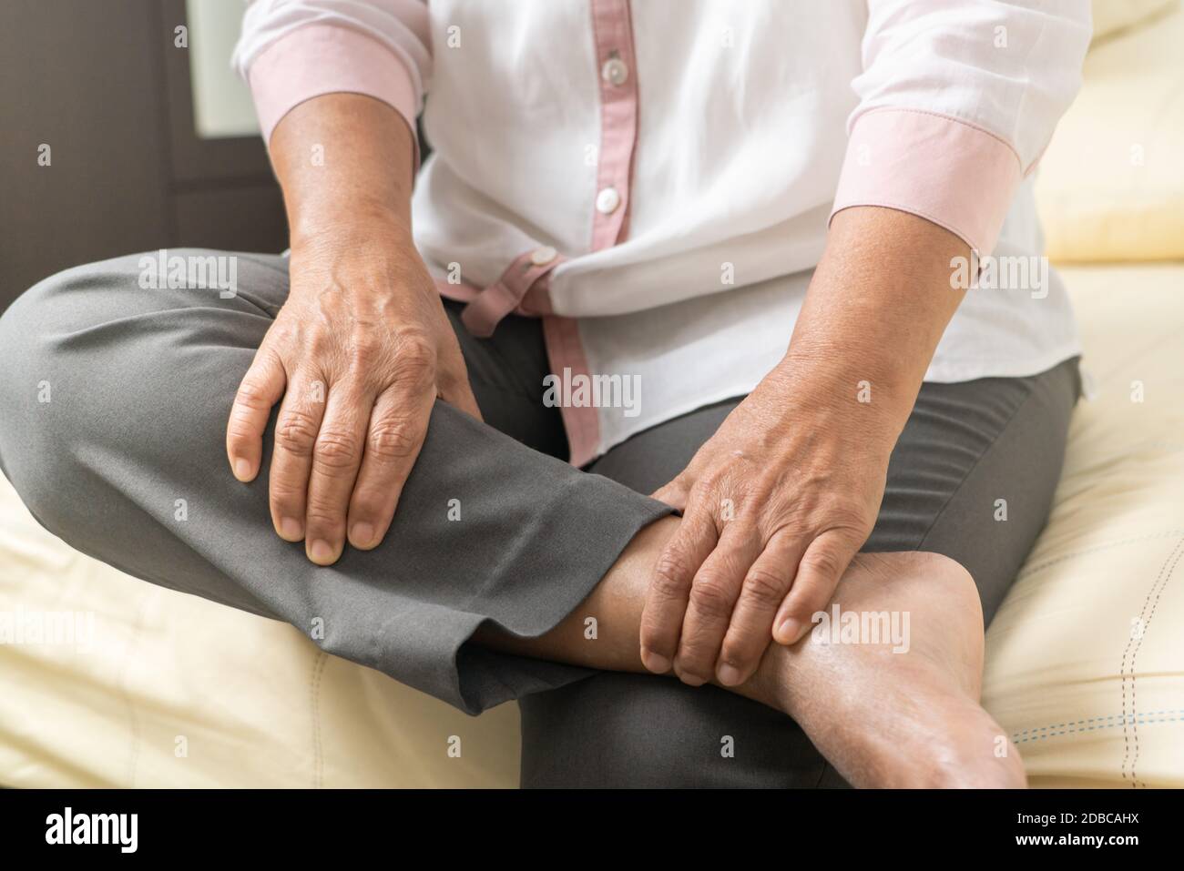 Bein Krampf alte Frau, die an Bein Krampf Schmerzen zu Hause, Gesundheitsproblem der Senior-Konzept Stockfoto
