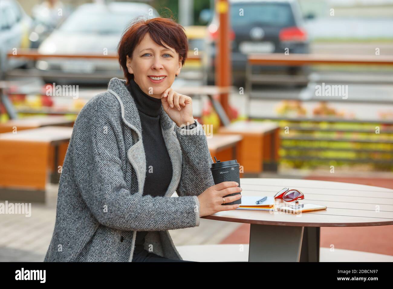 Porträt einer Frau, die an einem Tisch in einem Sommercafé sitzt. Stockfoto