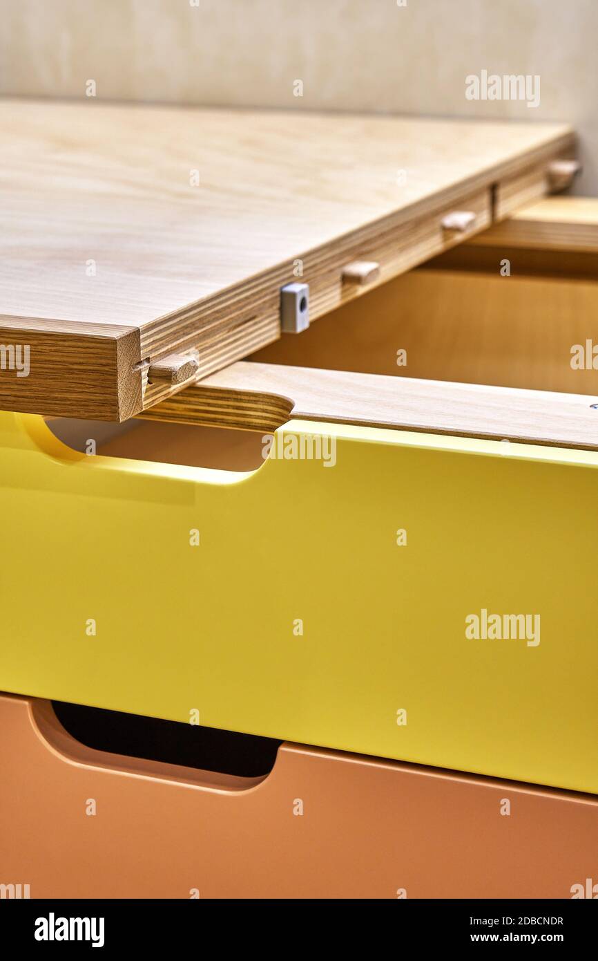 Sperrholz Schreibtisch mit mehrfarbigen Schubladen während der Montage. Fragment des Schreibtisches Stockfoto