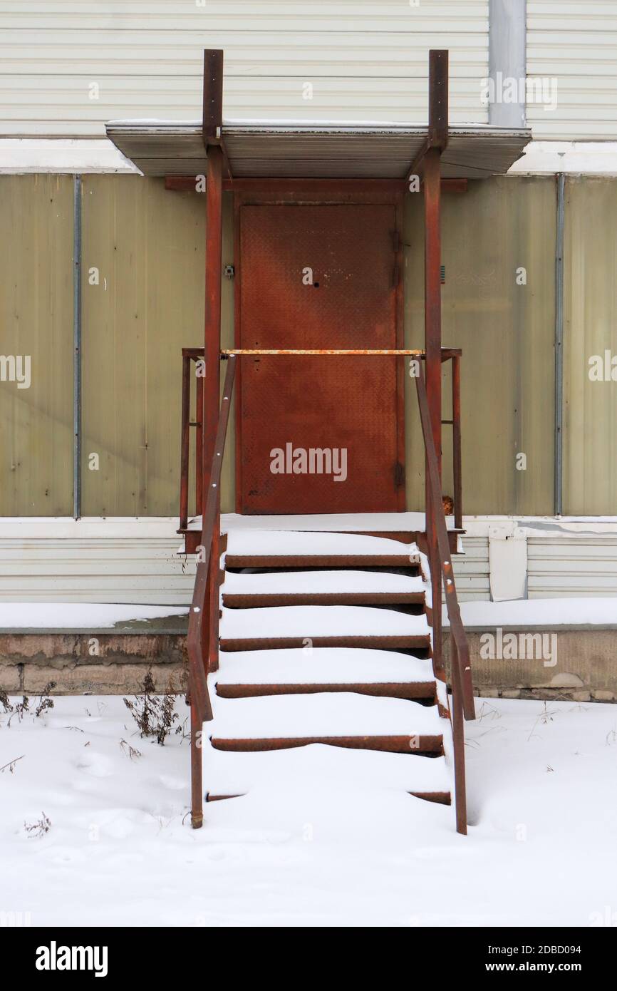 Rustikale Tür mit Treppen unter Schnee Stockfoto