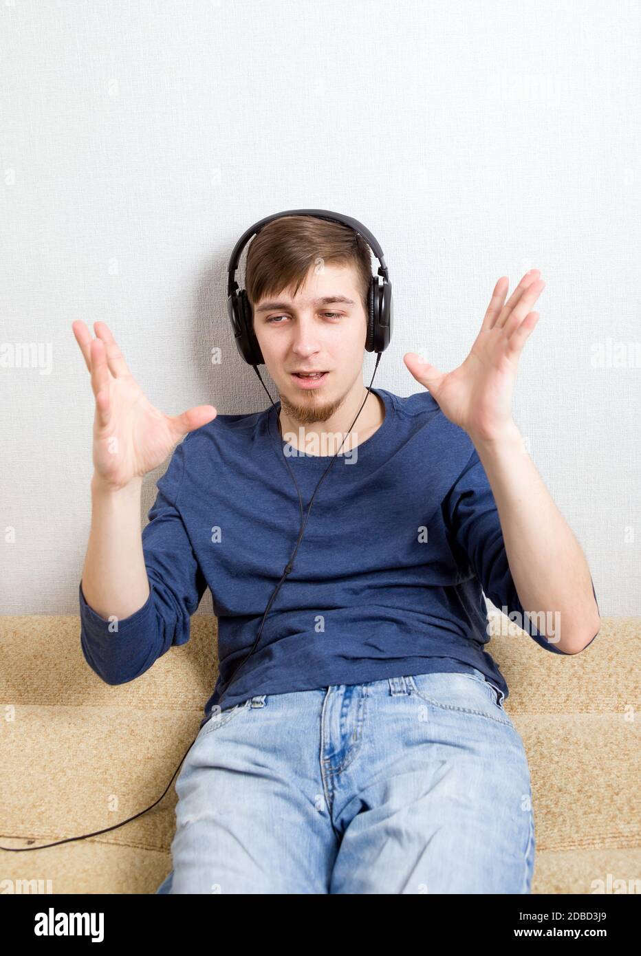 Glücklicher junger Mann in den Kopfhörern Hören Sie die Musik An der Wand Stockfoto
