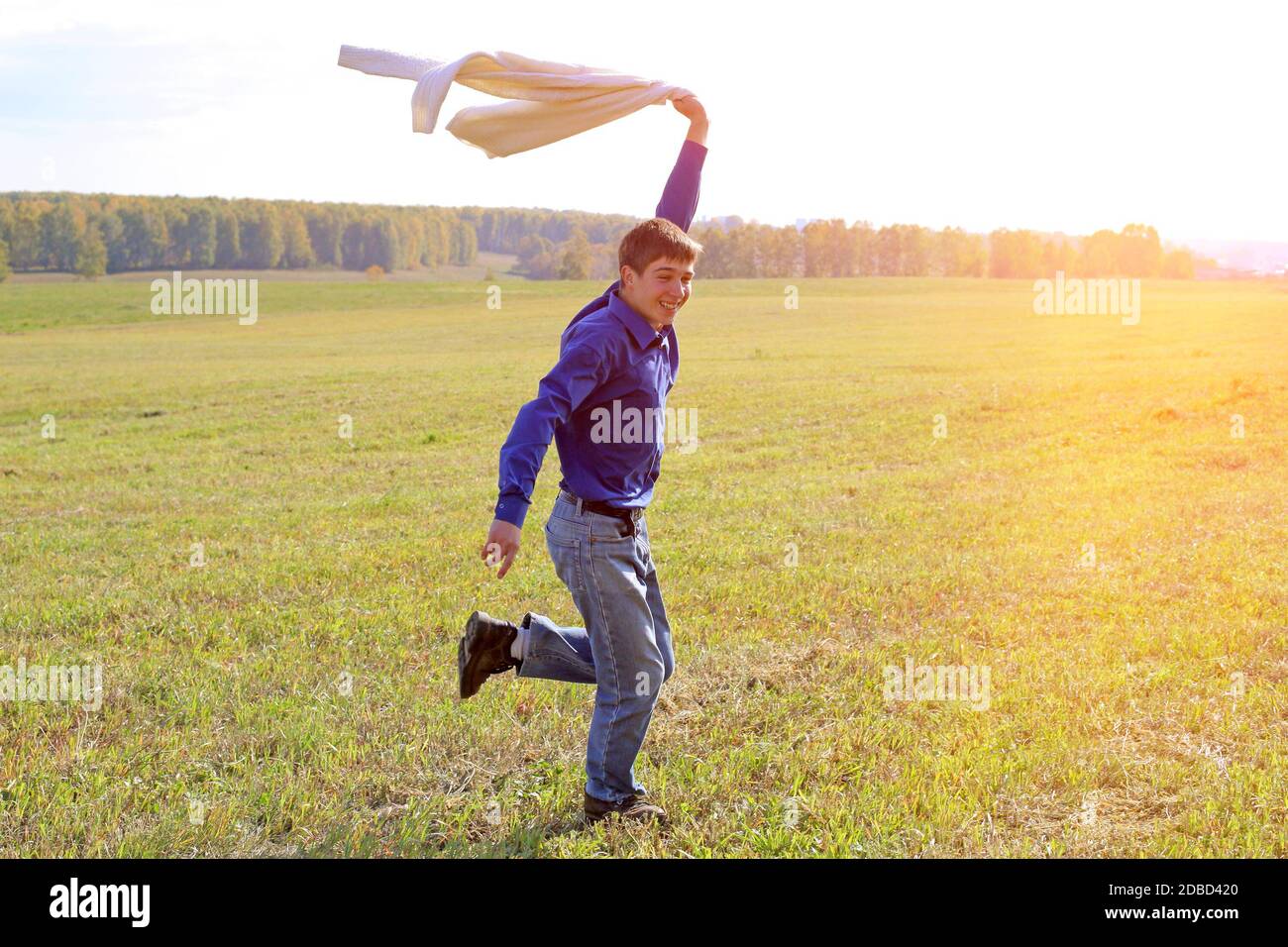 Glücklicher junger Mann, der auf dem Gras des Sommers läuft Ein Stockfoto