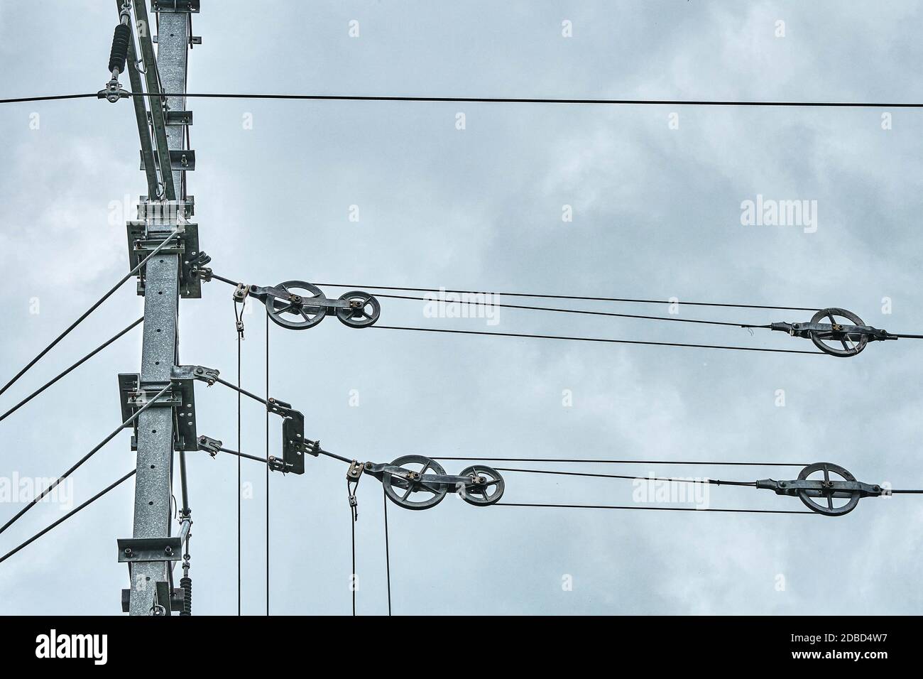 Die Fahrleitungen elektrifizierter Eisenbahnstrecken über dem Kopf gegen einen düsteren Himmel. Drahtspannung Stockfoto