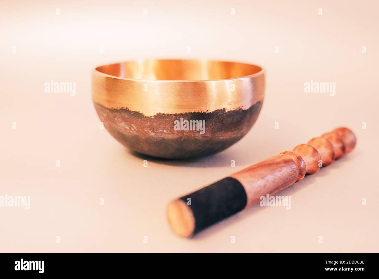 Bronze tibetische Klangschale mit Holzstab auf weißem Hintergrund. Klangheilung, Klangbadtherapie Stockfoto