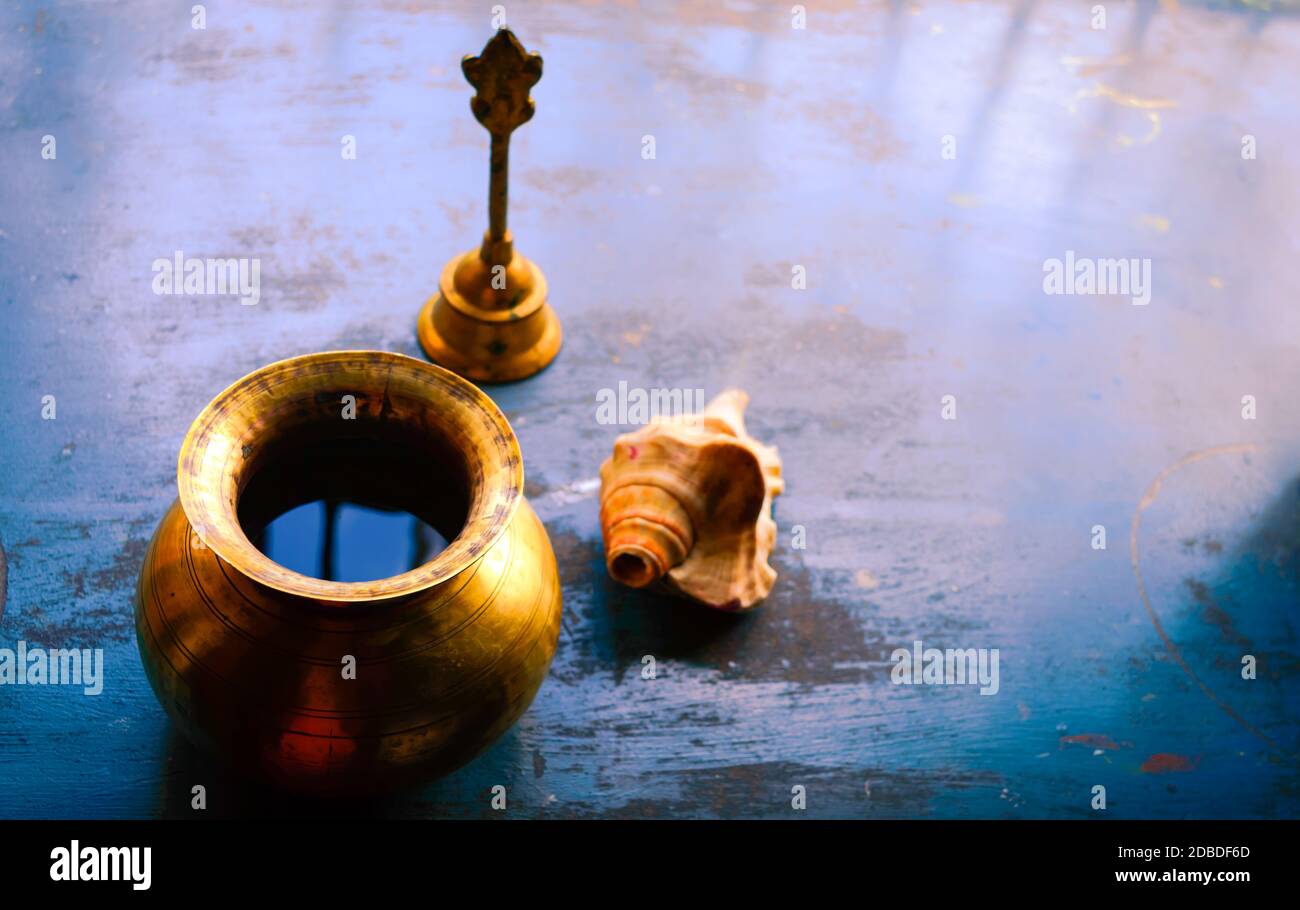 Close up Stillleben von antiken Holi Wassertopf und Glocke und Muschel auf rustikalem Boden. Glaube, Tradition, Spiritualität, Gebet, Symbole des Friedens und R Stockfoto