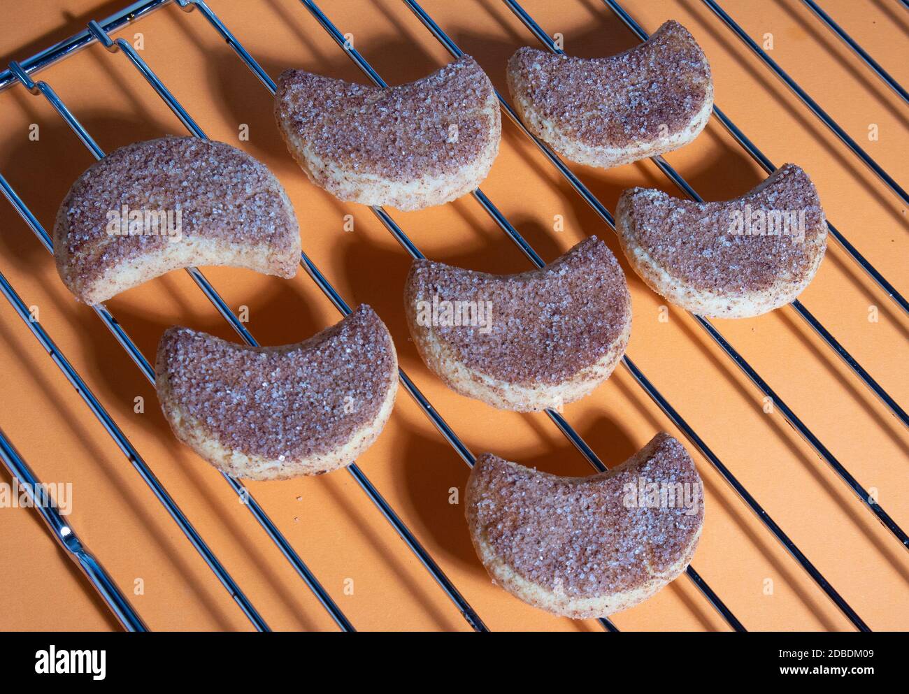 Eine Reihe von verlockenden halbunaren kandierten Keksen, die auf einem Metallrost liegen, harte Schatten Stockfoto