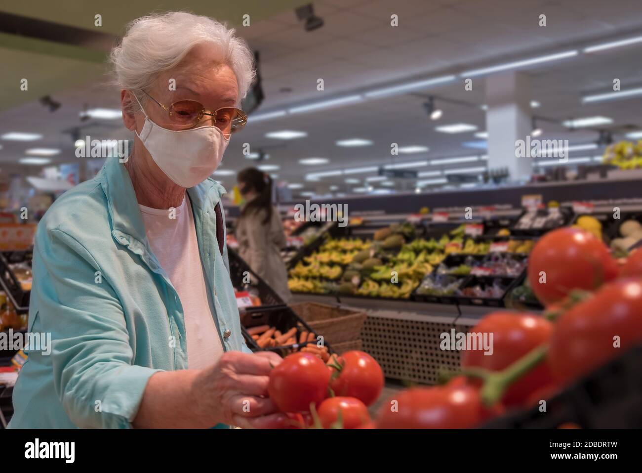 Ältere Frau mit Gesichtsmaske im Supermarkt Stockfoto