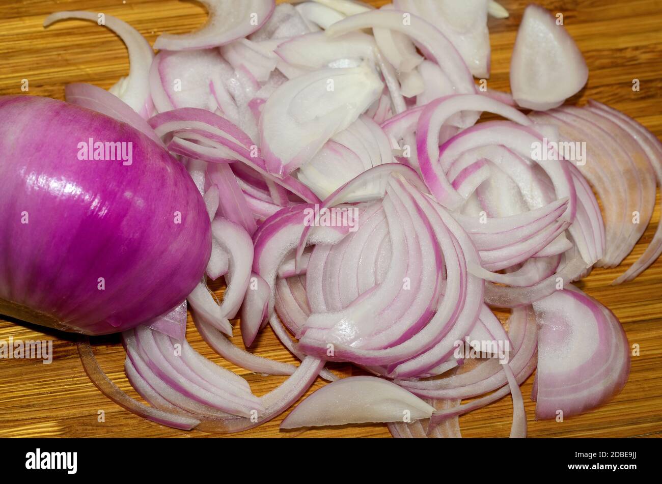 Nahaufnahme von dünnen geschnittenen Zwiebeln auf einem hölzernen Schneidebrett Stockfoto