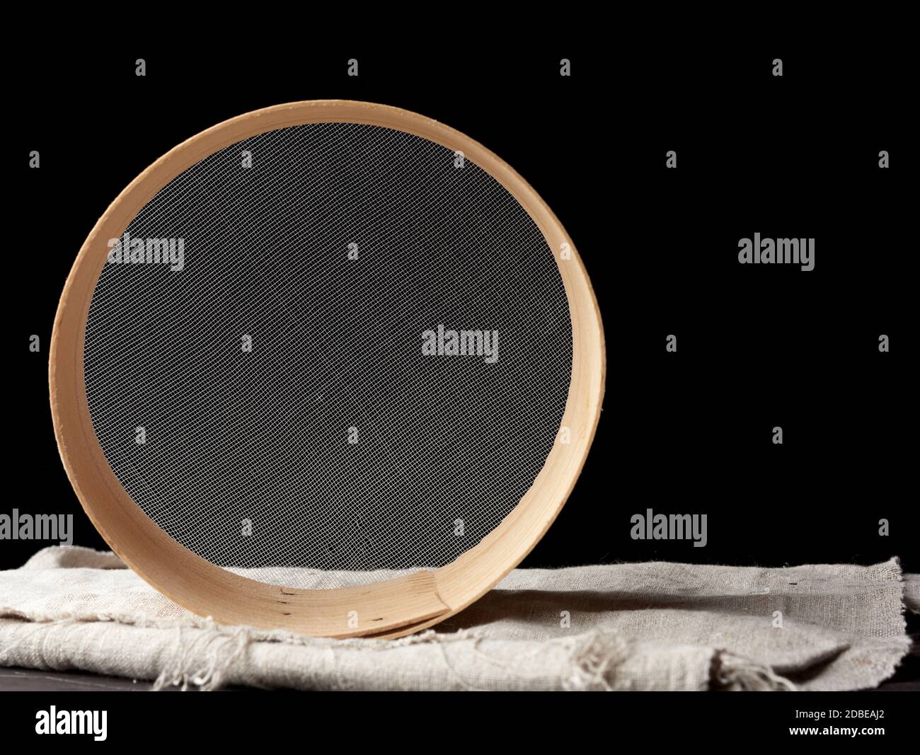Rundes Holzsieb auf schwarzem Hintergrund, veraltete Küchenutensilien, Kopierraum Stockfoto