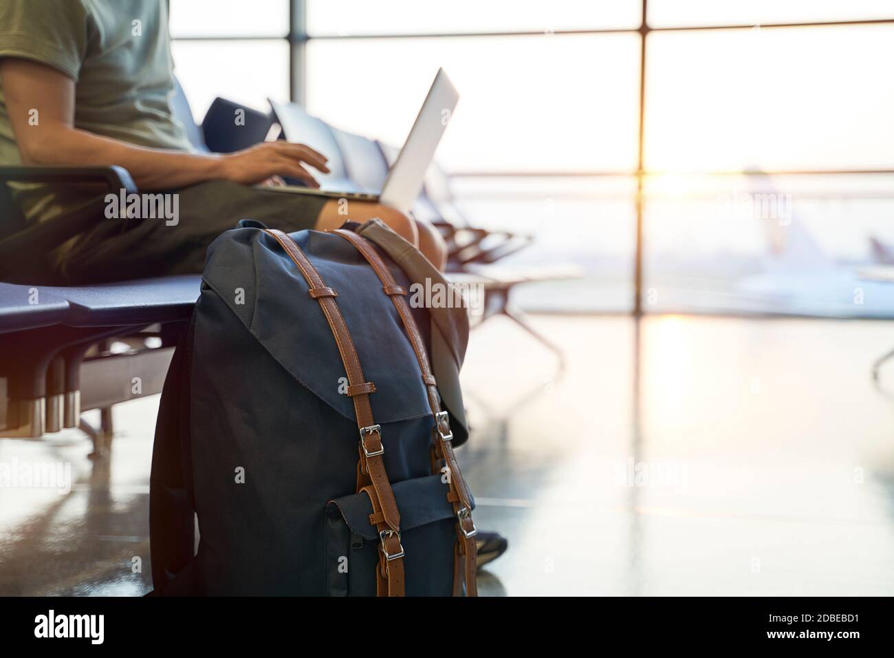 asiatischer Mann männliche Flugreisende sitzen im Wartebereich im Flughafenterminal Gebäude mit Laptop-Computer, konzentrieren sich auf den Rucksack Stockfoto