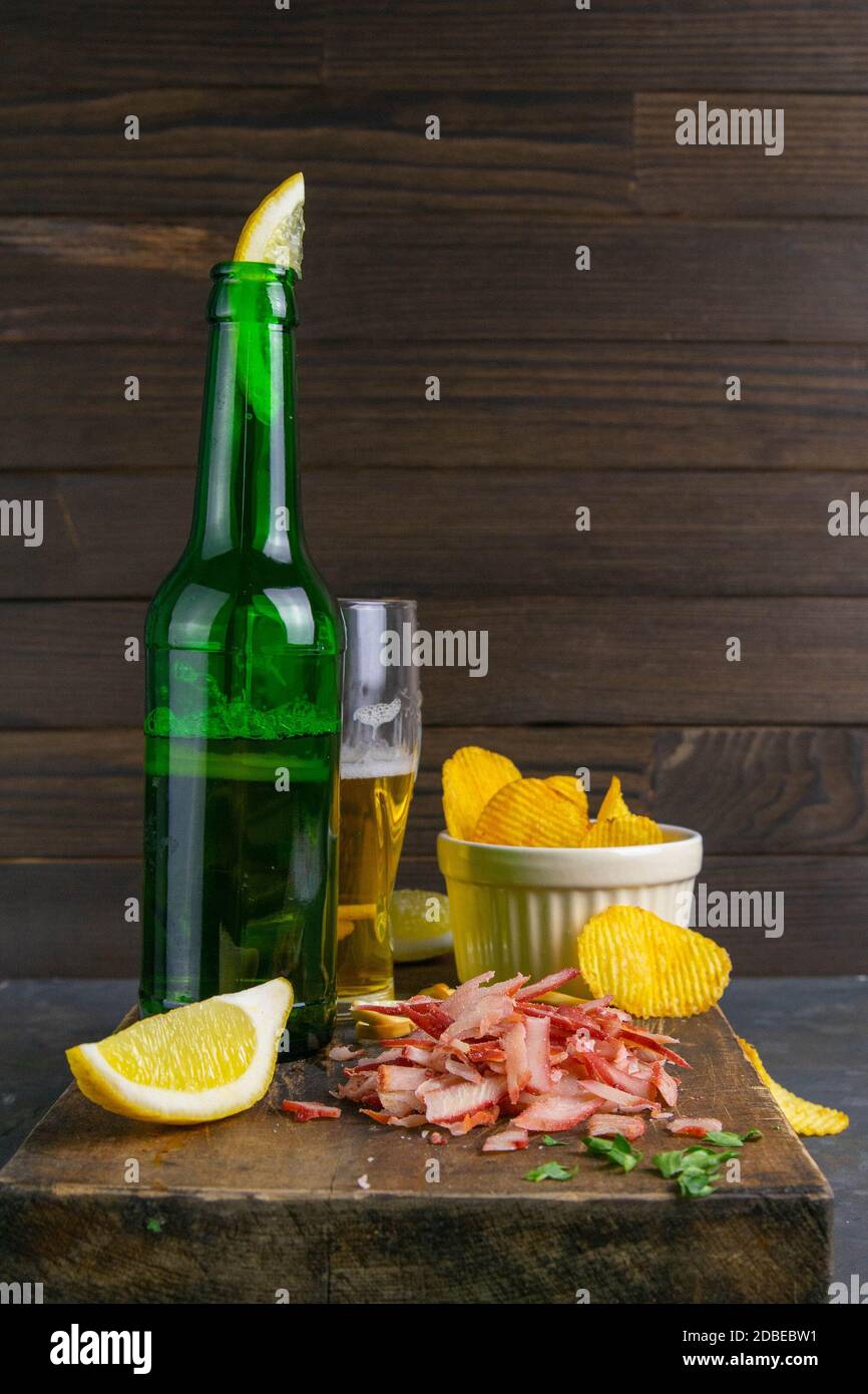 Krabbenringe mit Bier, Zitrone und Kartoffelchips auf dunklem Holzbrett. Snack auf Fisch mit Bier. Nahaufnahme. Stockfoto